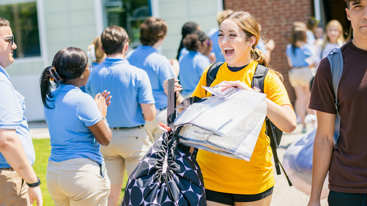 Students walks out carrying bag and papers