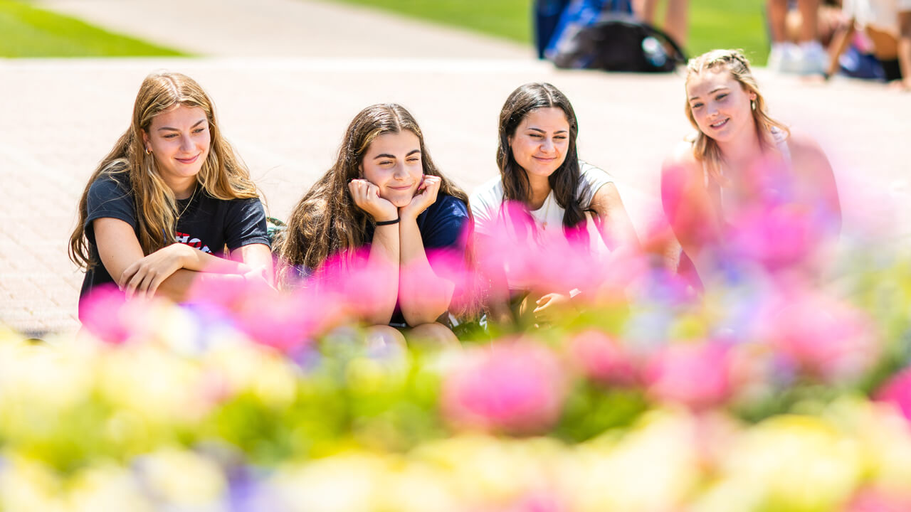 Students sit on the steps of the library