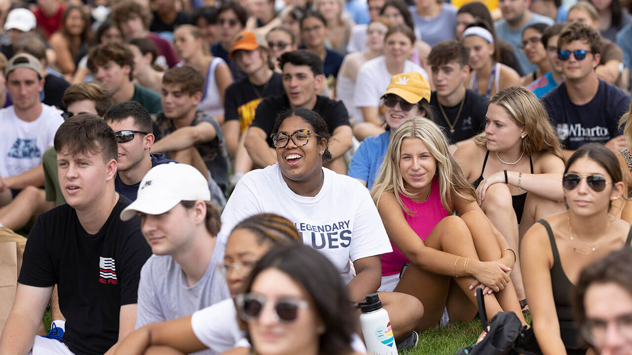 Hundreds of students laugh as they sit on the quad