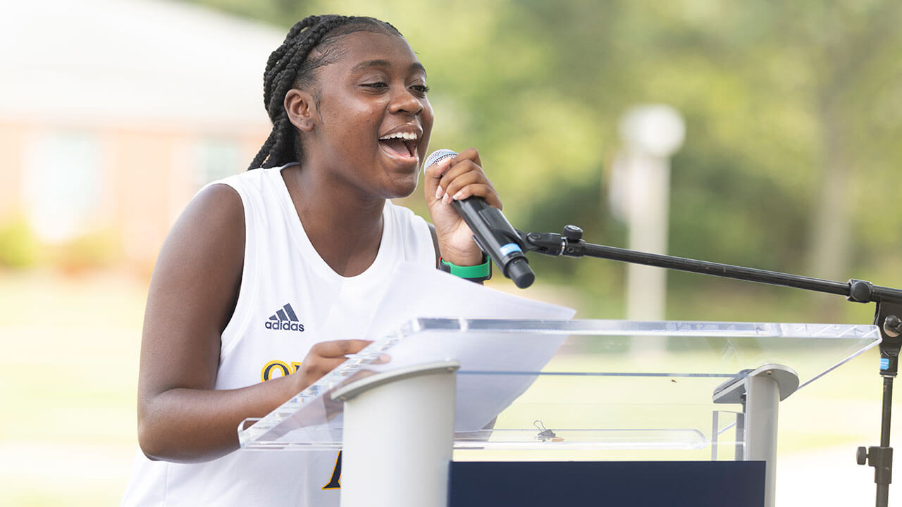 SGA president Owenea Roberts speaks from a podium on the quad