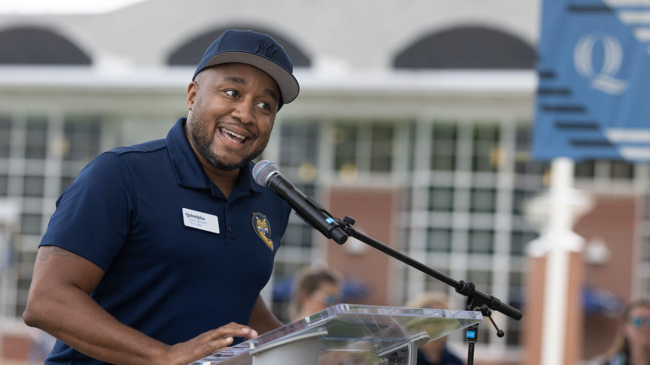 Don Sawyer speaks from a podium to first-year students on the quad