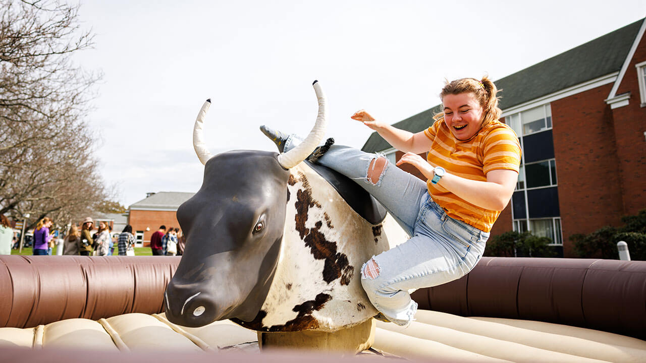 Fall Fest attendee riding the bull at Fall Fest 2023