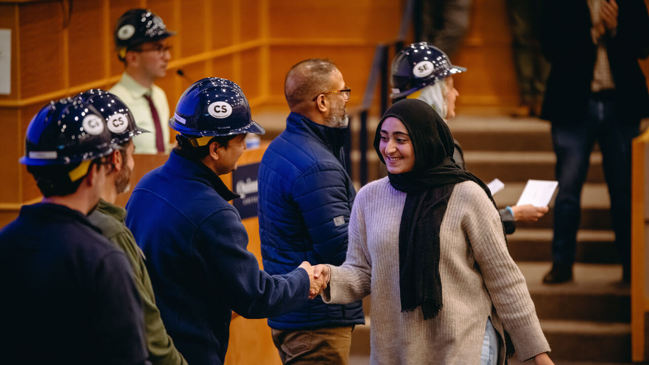 A student accepts their hard hat from presenters.