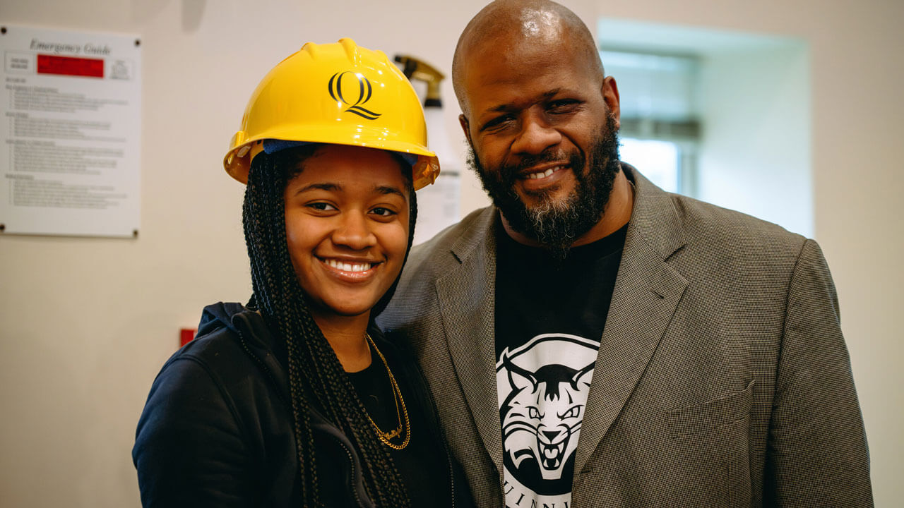 Individuals smiling for a photo and from the right a woman wears a hard hat