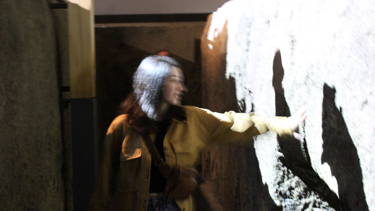 student reaches out to a trench wall in the dark