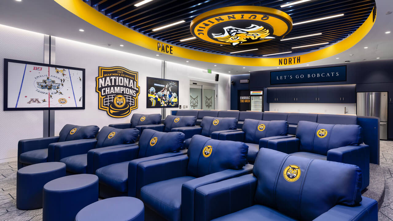 Wide shot of chairs in men's ice hockey locker room.