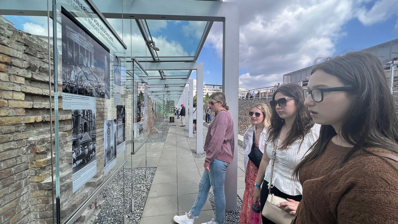 Students reading excerpts of events from the holocaust tucked beneath glass