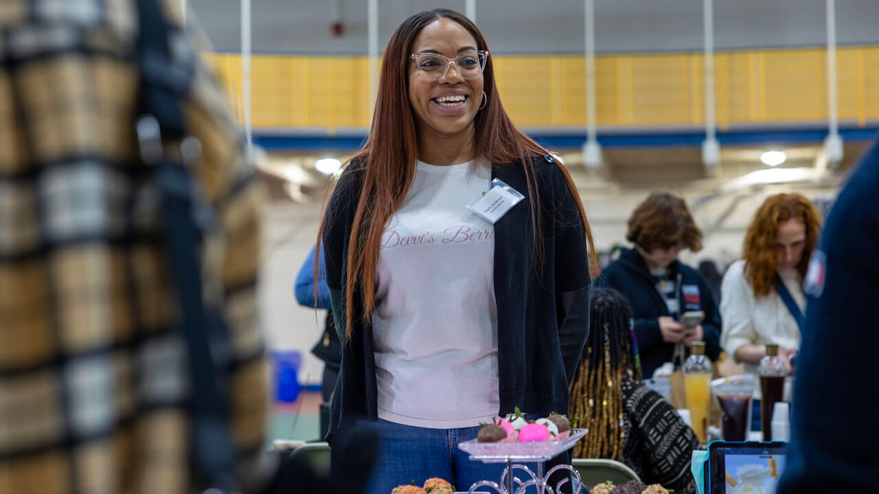 A vendor at Devvi's Berries smiles in front of their table.