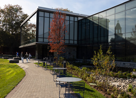 Exterior of the RecWell building with the library clocktower reflected on a wall of windows