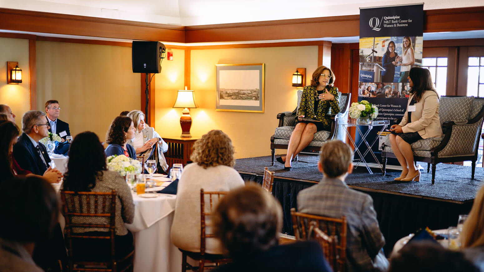 2 women speaking on a raised stage