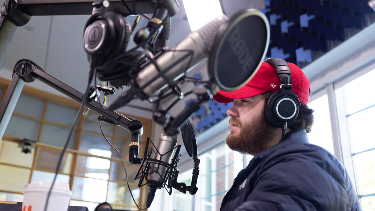 A male student speaking into a podcast microphone