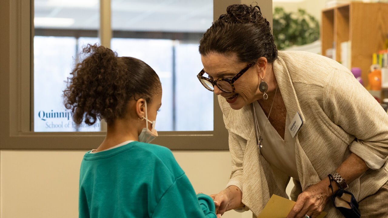 an older woman shaking a young girl's hand