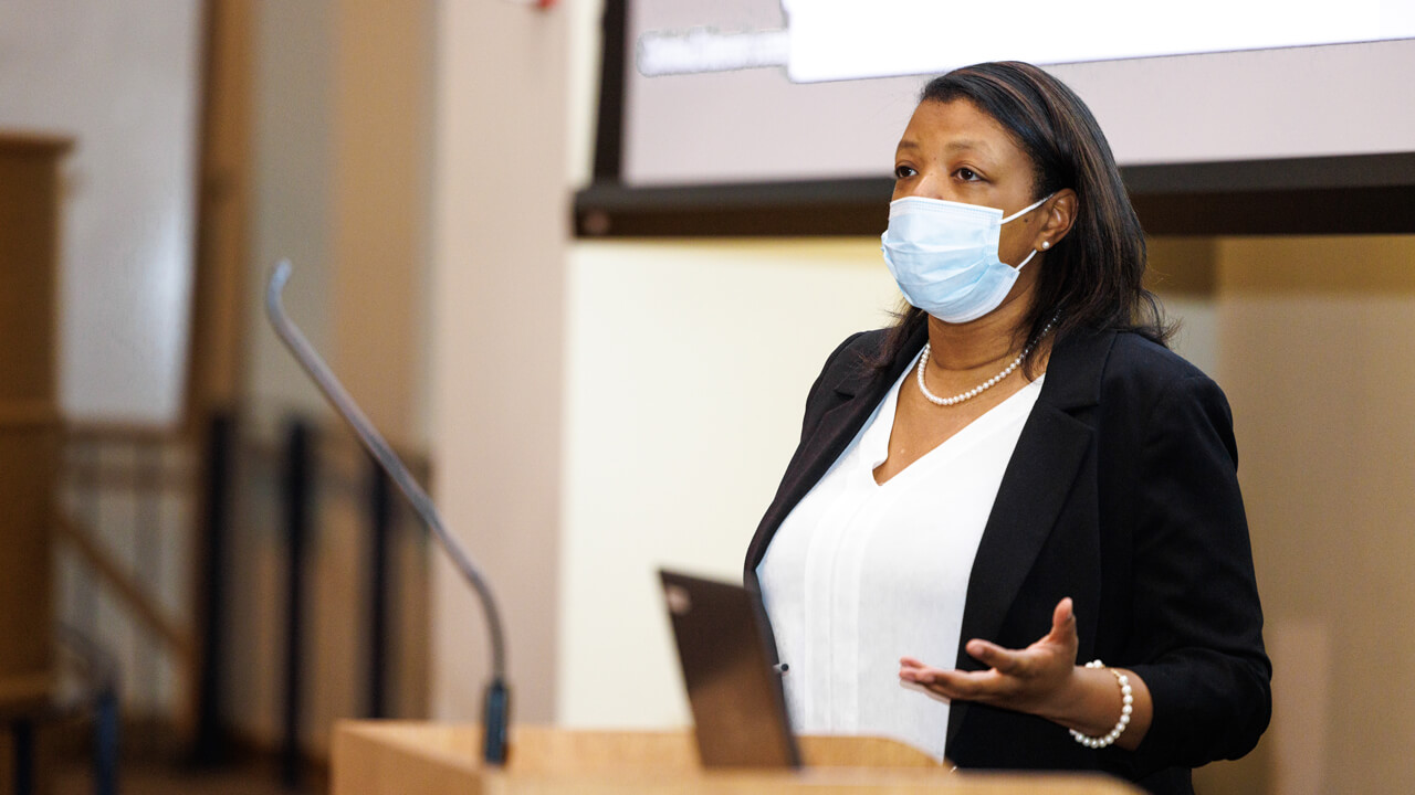 Christina Dickerson speaks with a mask at a podium during a Black History Month event at Quinnipiac