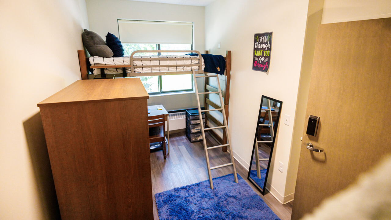 Bunk beds by a window next to a wardrobe in a bedroom