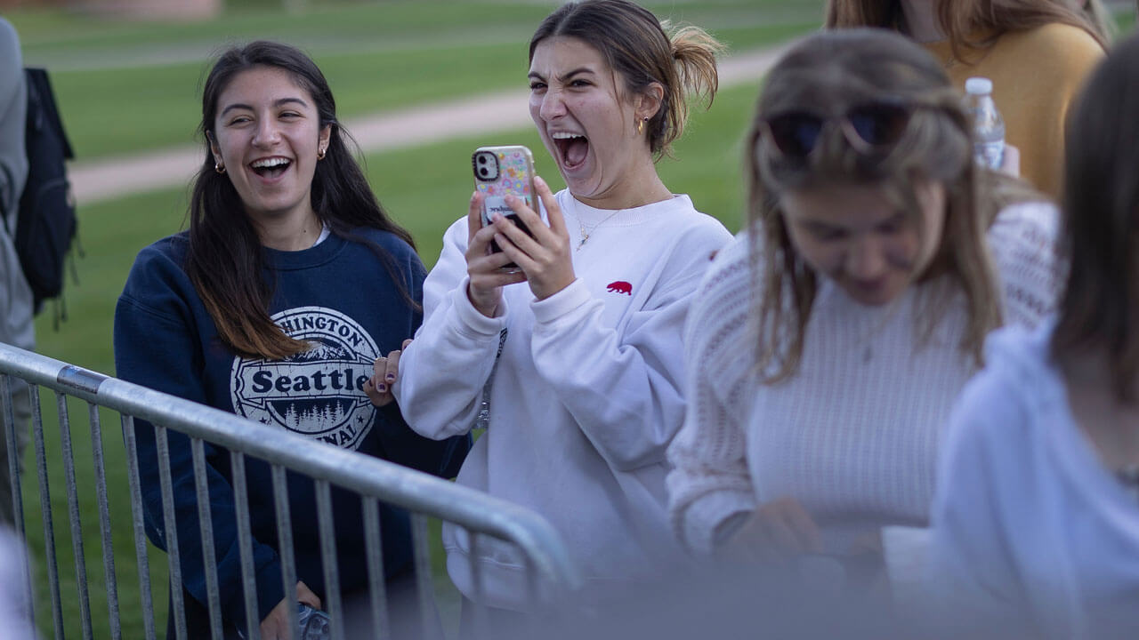 Girls cheering and holding their phones for Fall Fest performance