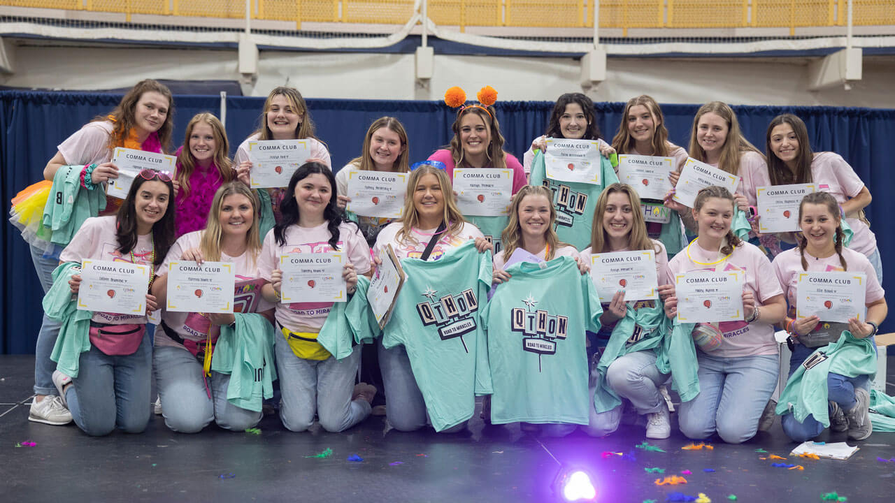 Quinnipiac students holding up QTHON shirts and certificates