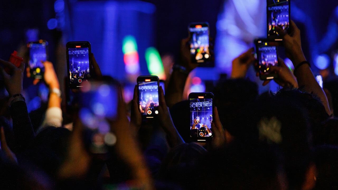 Crowd of students holding up their phones to take videos of concert