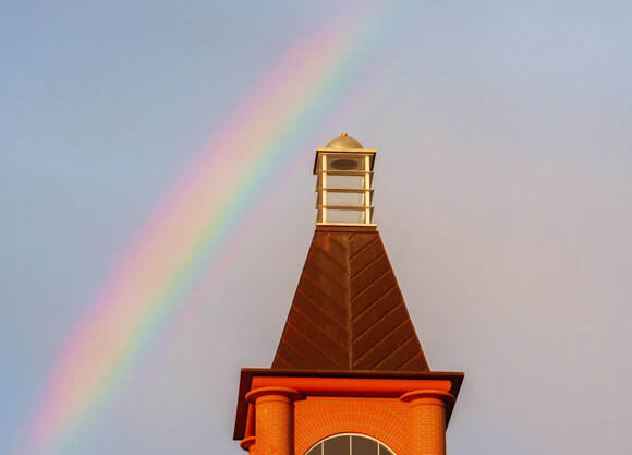 A rainbow in the sky over the Arnold Bernhard Library at dusk