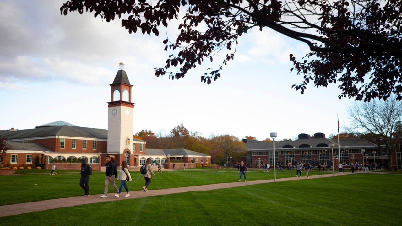 Dozens of students walk across the Quinnipiac quad in the autumn