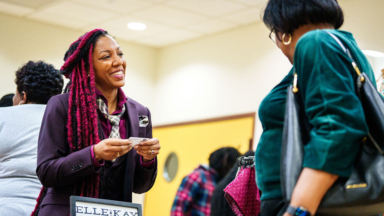 A vendor at the Sip & Shop event speaking with a customer.