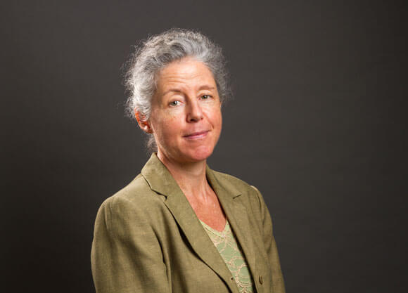 Elena Bertozzi smiles for a headshot wearing a green blazer.