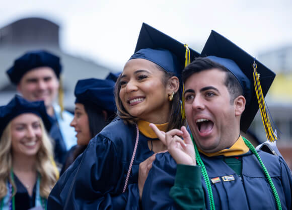 Two health sciences graduates smile broadly and pose for a photo on Commencement day