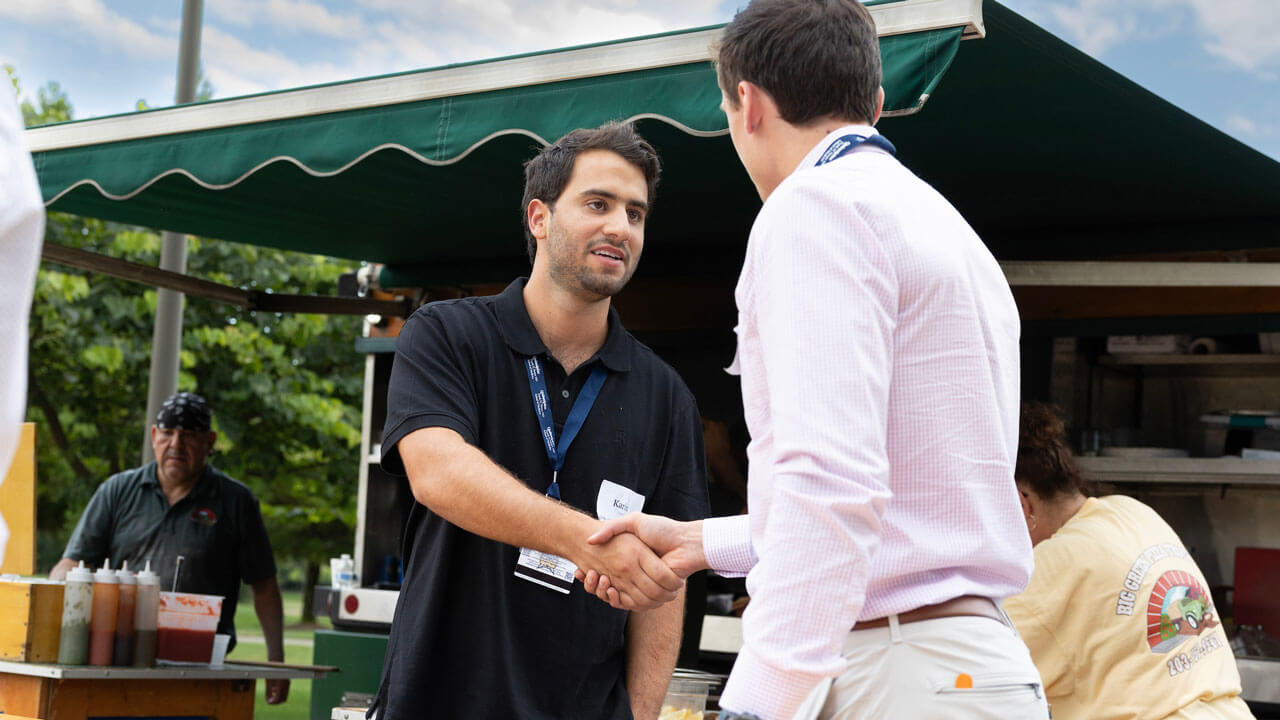 Two men shaking hands in front of concession stand