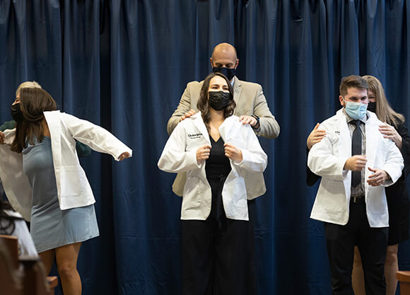 Students receive their white coats.