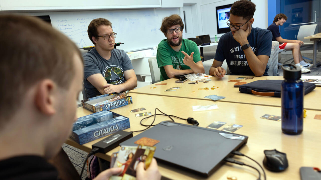 Group of high schoolers sitting at a table looking at card games