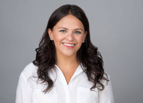 Taylor Rahe smiles in a white shirt for a headshot..