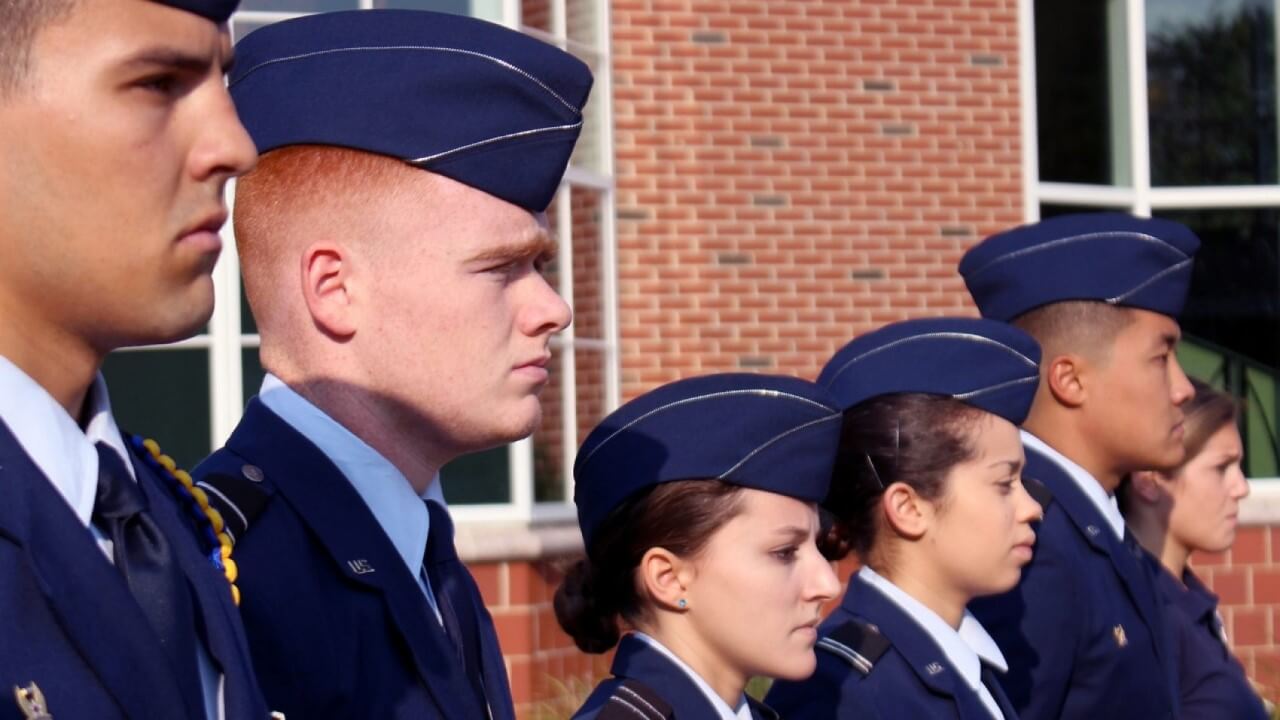 Veterans stand in a line in their military garb.