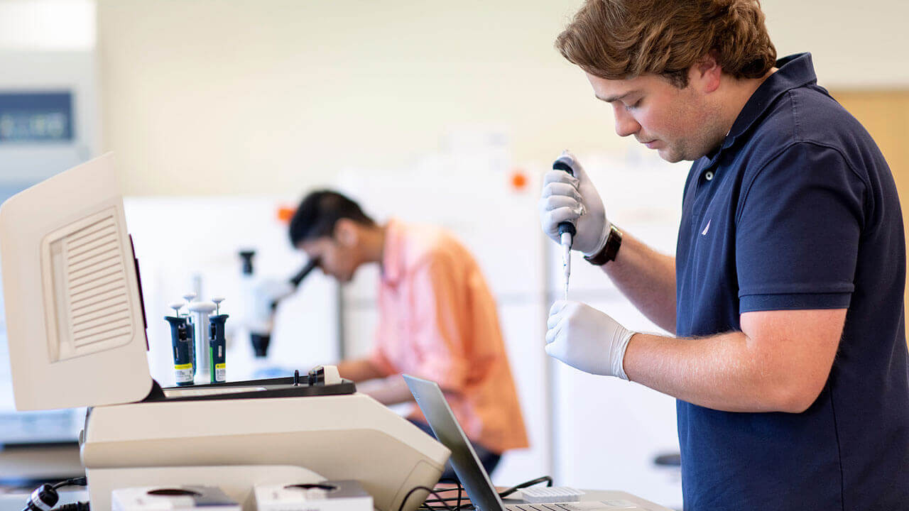 A student uses an eye dropper to move liquid into a test tube in a lab