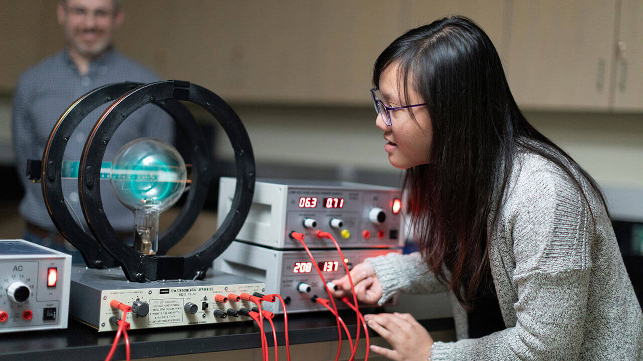 A biochemistry student observes a large machine operating in a lab classroom