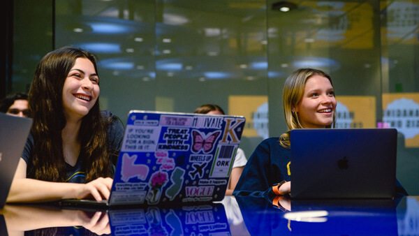 Students take notes on their computers during a lecture.