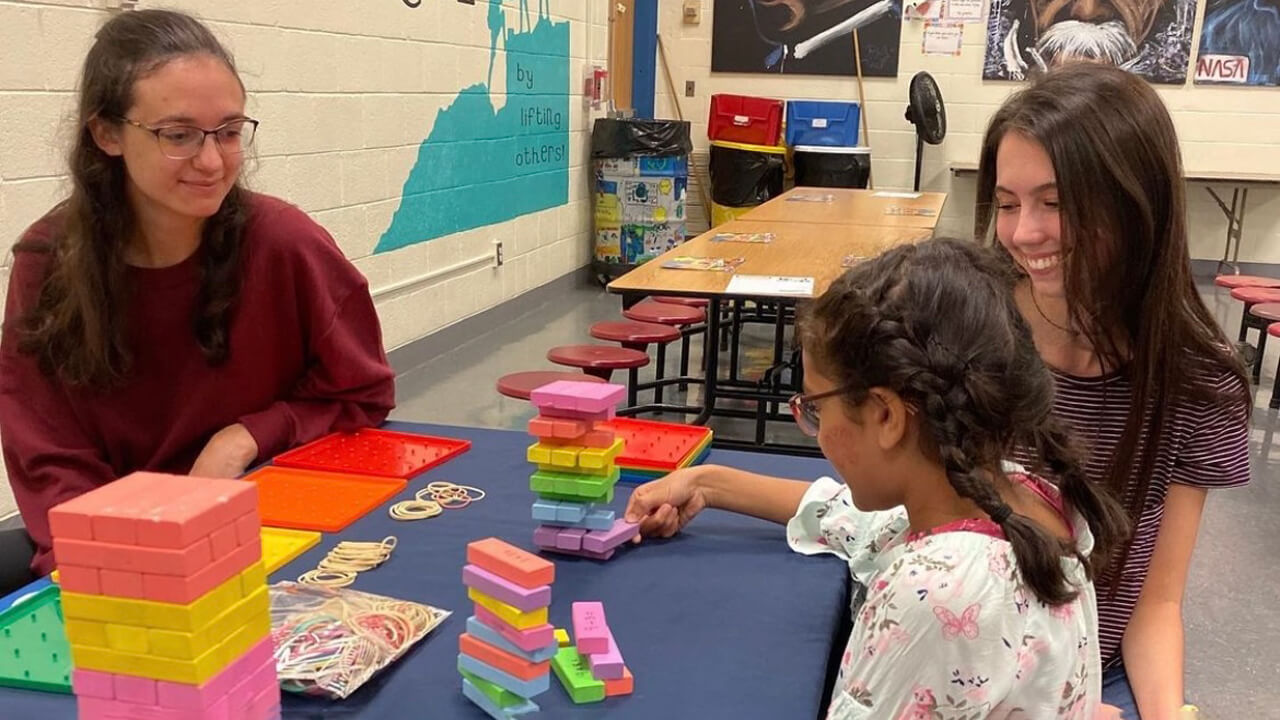 Quinnipiac University education student sits with kids in a classroom.