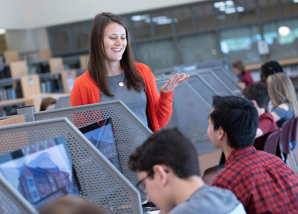 School of Education graduate student Gillian Clark works with students in the computer lab at North Haven High School