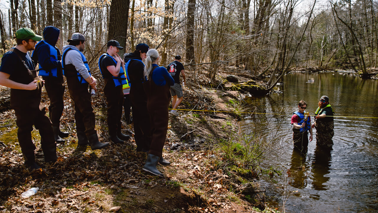 Civil engineering students measure streamflow with the USGS at the Mill River.