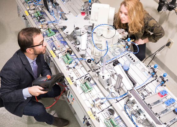 Professor Kiassat works with a student on the automatic assembly process machine.