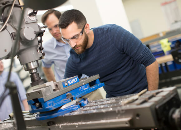 A male student working on a manufacturing machine