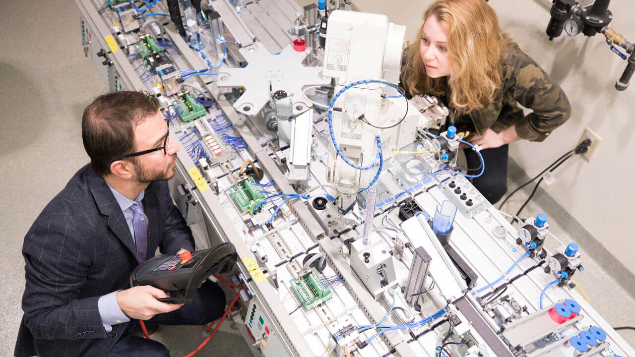 A student and professor look at an automatic production line