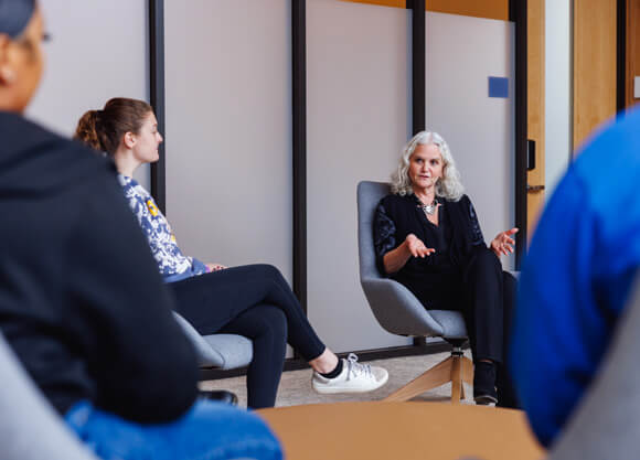 A woman speaking to a circle of young adults