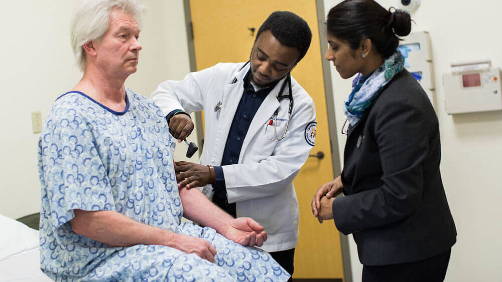 A medical student checks a patient's blood pressure under guidance of his professor