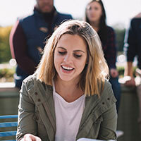 School of Nursing student flipping through a textbook outside on the North Haven Campus