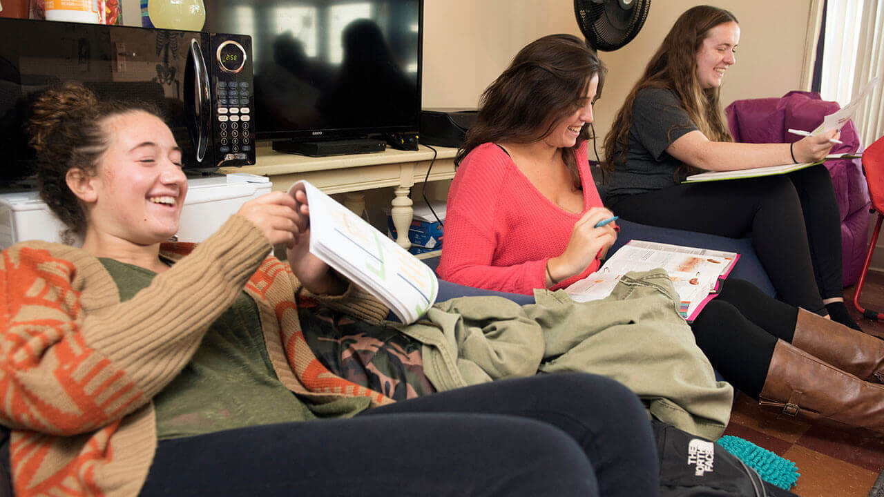 Three nursing students laugh together in their dorm