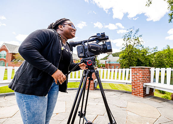 woman outside using a video camera on a tripod