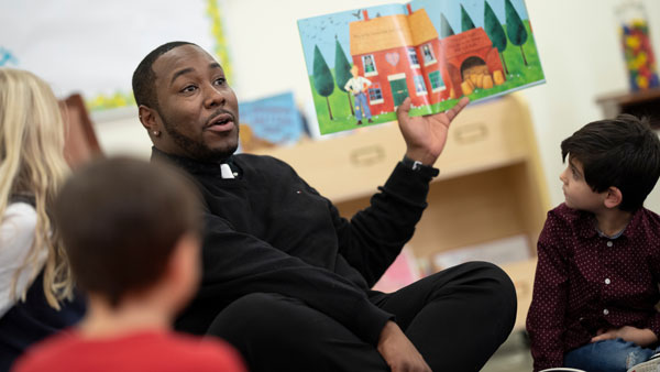 An education graduate student reads a book to children.