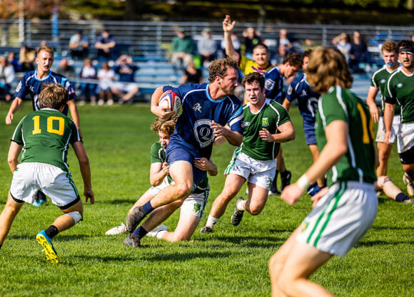 Group of men running down field playing rugby