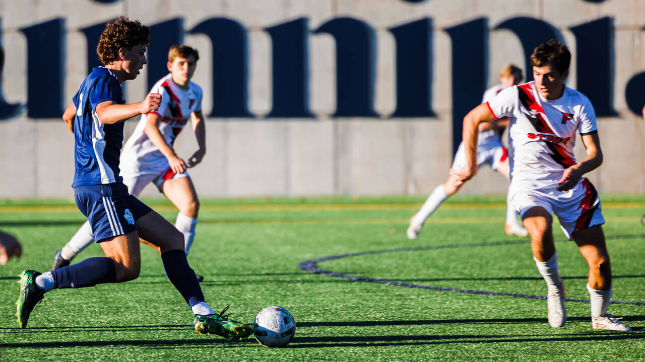 Student kicking soccer ball to teammates