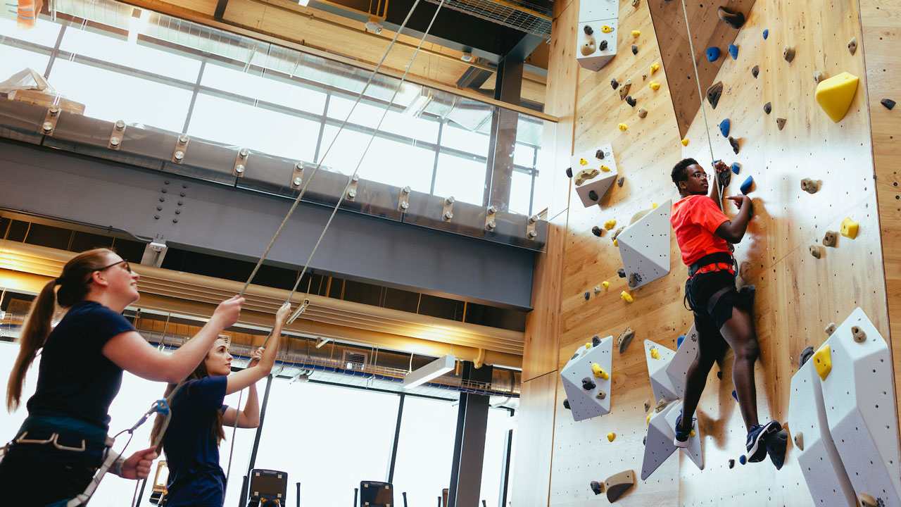 Man climbing the rockwall with assistance