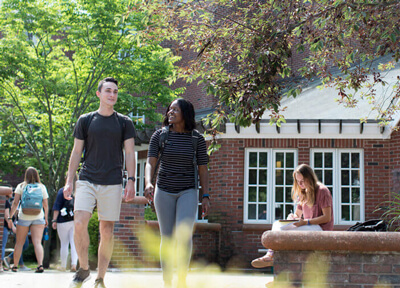 Two students talk as they walk by residence halls